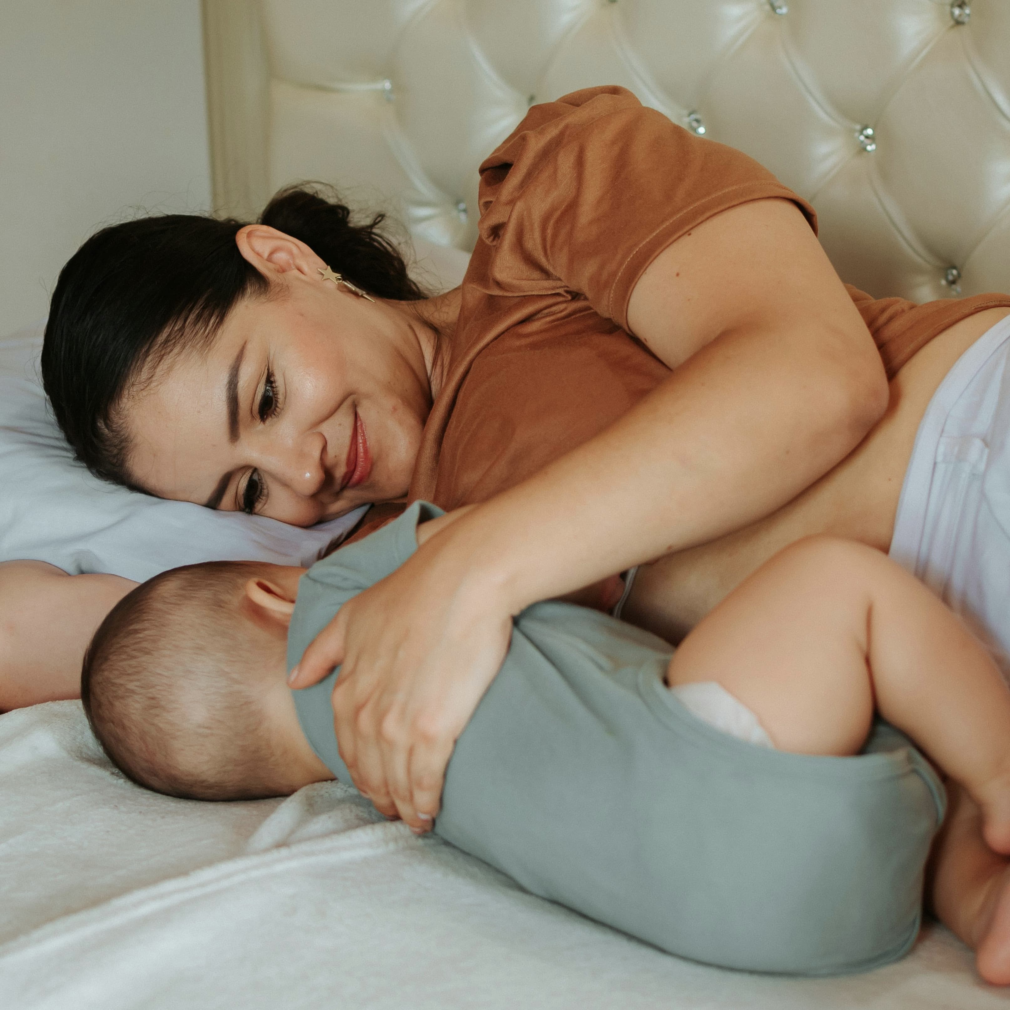 A joyful mother cuddles her newborn in a soft, sunlit bedroom—highlighting the beauty of post-pregnancy life. This image reflects the emotional and physical journey of motherhood. In this AEDITION article we cover non-invasive mommy makeover treatments aimed at helping women restore confidence and feel their best after childbirth.